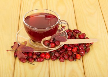 Rose hips ahşap arka plan üzerinde cam bardak