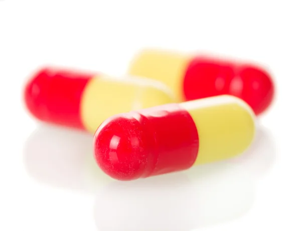 Macro. Red and yellow capsules isolated on white — Stock Photo, Image