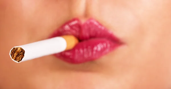 Сигарета на фоне женских губ с красной помадой — стоковое фото