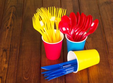 Çok renkli, tek kullanımlık çatal ve koyu ahşap arka plan üzerinde gözlük