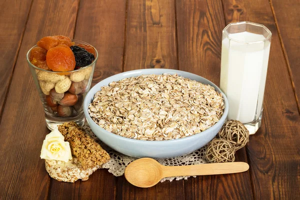 Gesunde Ernährung für Erwachsene: Haferflocken, Milch, Nüsse, Trockenfrüchte auf dunklem Holz — Stockfoto