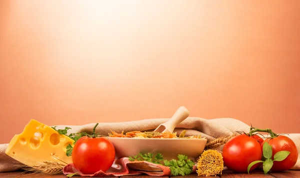 Сырая паста, помидоры и сыр на розовом фоне — стоковое фото