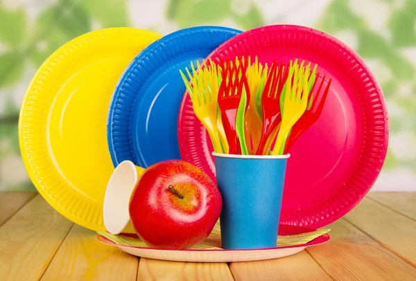 Bright, disposable tableware on abstract green — Stock Photo, Image