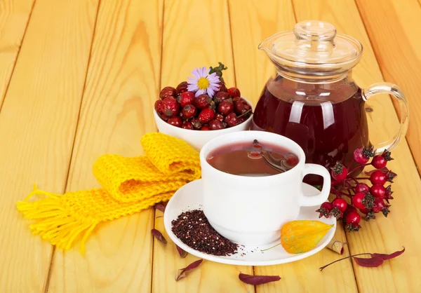 Caraffa e tazza bevanda rosa canina su sfondo di legno chiaro — Foto Stock