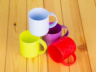 Plastik çok renkli bardak hafif ahşap arka plan üzerinde.