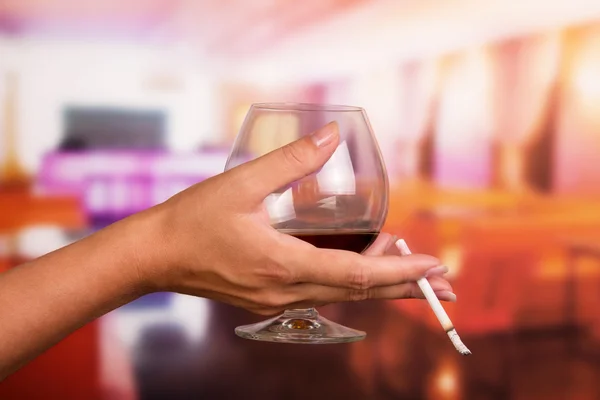 Mano femenina sosteniendo vaso de whisky y cigarrillo en el fondo del restaurante — Foto de Stock