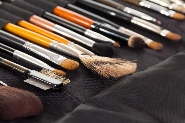 Definir escovas cosméticas para maquiagem no fundo tecido escuro . — Fotografia de Stock
