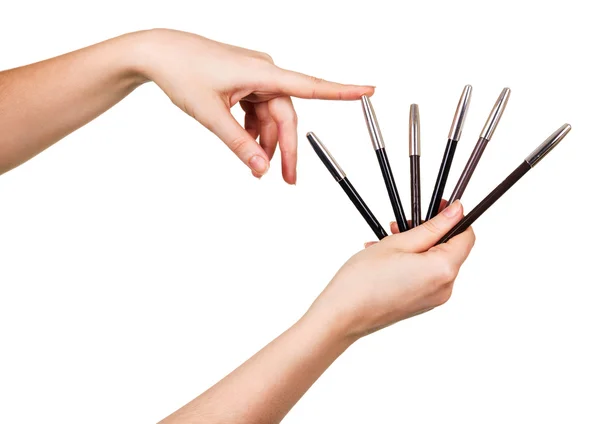 Womens hands are holding sticks makeup isolated on white. — Stock Photo, Image