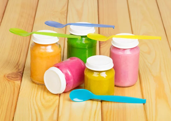 Glass colorful jars of baby food on background light wood. — Stock Image Glass colorful jars of baby food on background light wood. Royalty Free Stock Photos