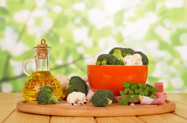 Brócolos frescos, couve-flor e óleo em decantador em verde abstrato . — Fotografia de Stock