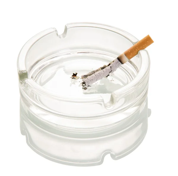 Rozkładające się papierosa w popielniczce szkła na białym tle. — Zdjęcie stockowe