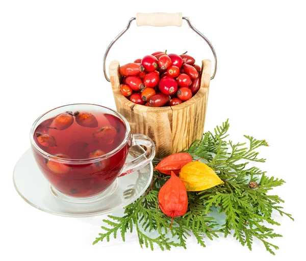 Holzeimer mit Beeren Wildrose und Tasse Tee isoliert. — Stockfoto