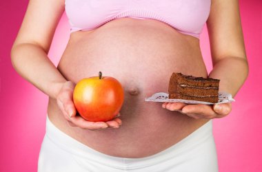 Kolay ve apple, pembe arka plan tutan hamile kadın.