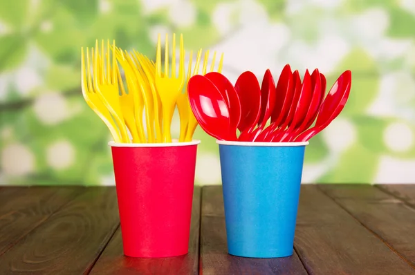 Bright plastic disposable tableware on abstract green. — Stock Photo, Image