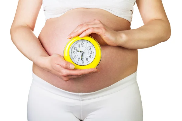 Έγκυος γυναίκα που κρατά ρολόι συναγερμών που απομονώνονται σε λευκό. — Φωτογραφία Αρχείου