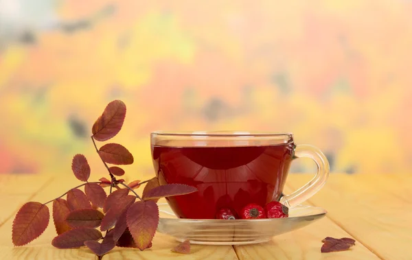 Taza de té bayas de rosa mosqueta sobre el fondo hojas de otoño . — Foto de Stock