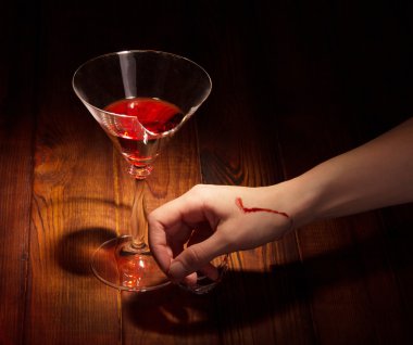 Kırık kadeh şarap ve koyu renk ahşap karşı kıyılmış el.