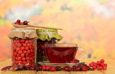 Rowan çilek, yaban gülü ve fincan çay sonbahar yaprakları üzerinde.