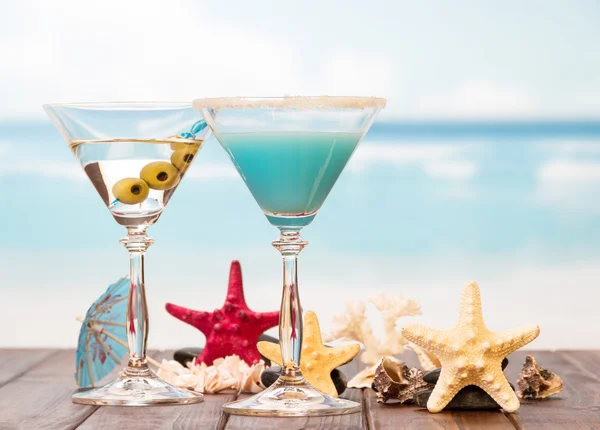 Cocktails, zeesterren en wastafels op zee achtergrond. — Stockfoto