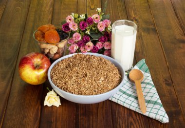 Fındık üzerinde koyu renkli ahşap kase buğday gevreği, cam süt, elma,.