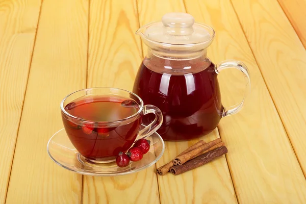 Jarra con bebida, taza de té bayas de rosa mosqueta en madera clara . — Foto de Stock