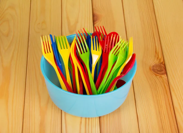 Ciotola di plastica colorata, forchetta e cucchiaio su sfondo legno chiaro . — Foto Stock
