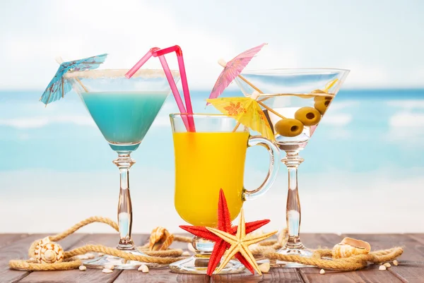 Due cocktail, succo di vetro, stelle marine e conchiglie sullo sfondo del mare . — Foto Stock