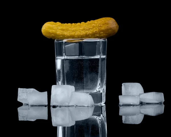 Glass  vodka, pickled cucumber and ice cubes isolated on black. — Stock Photo, Image