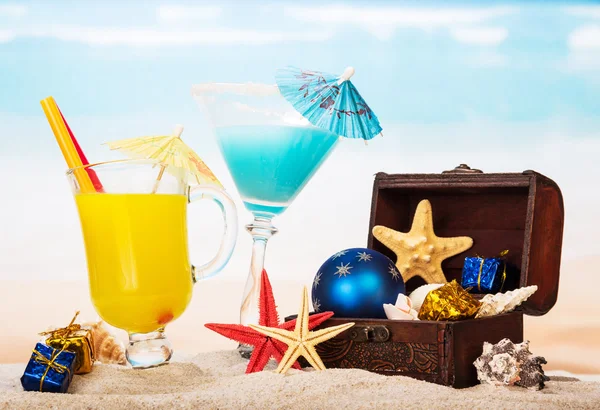 Cocktail, succo d'arancia, stelle marine, tesoro nella sabbia contro il mare . — Foto Stock