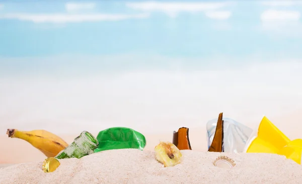 Sobras, pieles de plátano, plástico, botellas de vidrio en arena contra el mar . —  Fotos de Stock