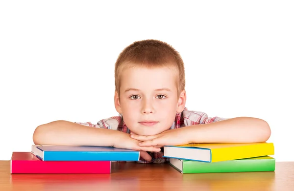 Lindo niño sentado en la mesa con libros en blanco . —  Fotos de Stock