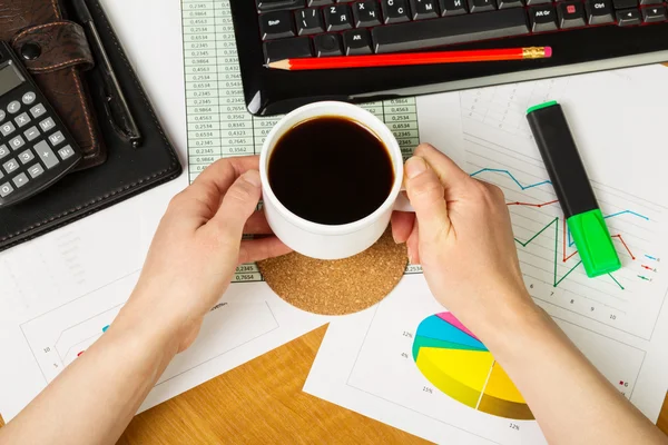 Kopp kaffe i händerna man, tangentbord, kalkylator på bakgrunden skrivbord. — Stockfoto