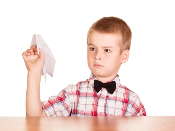 Siedzi w tabeli ładny chłopiec z papieru samolot w ręku. — Zdjęcie stockowe