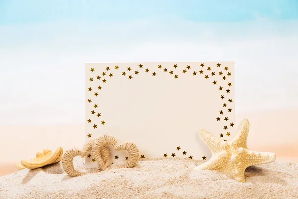 Blank greeting card, starfish, heart in sand against the sea. — Stock Photo, Image