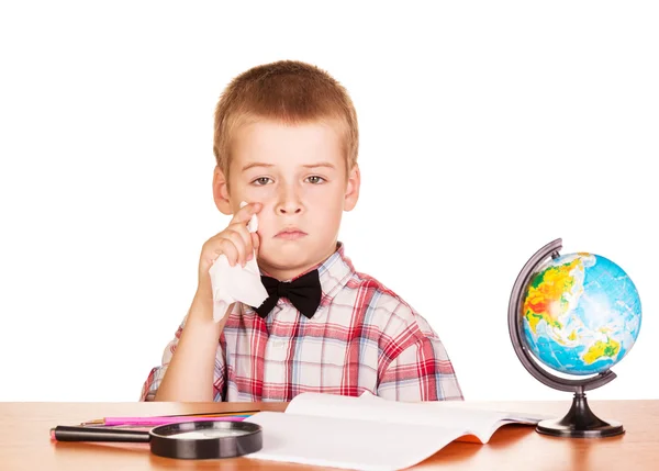 Triste ragazzo siede a tavola con notebook e globo isolato . — Foto Stock