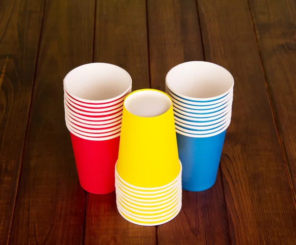 Tasses jetables lumineuses sur fond de bois foncé . — Photo