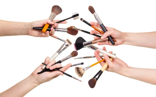 Les mains des femmes tiennent des pinceaux cosmétiques pour le maquillage isolé sur blanc . — Photo