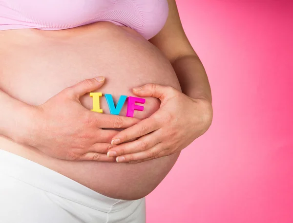 Zwangere vrouw met Ivf belettering op een roze — Stockfoto