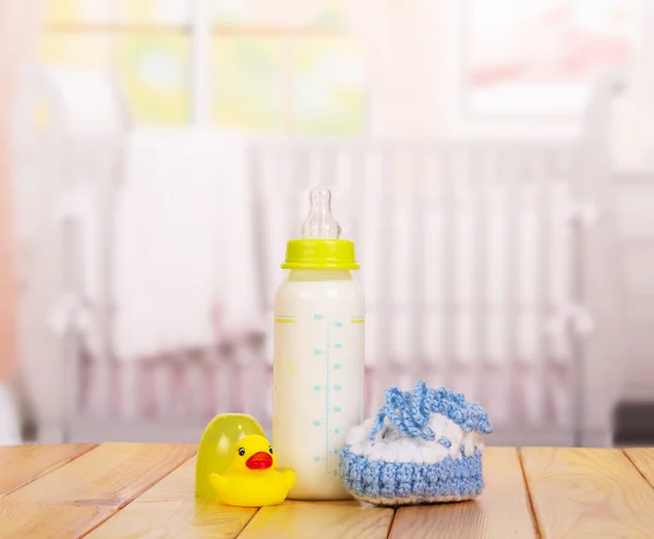 Láhev mléka, modré botičky a gumovou kachnu izolované na bílém — Stock fotografie