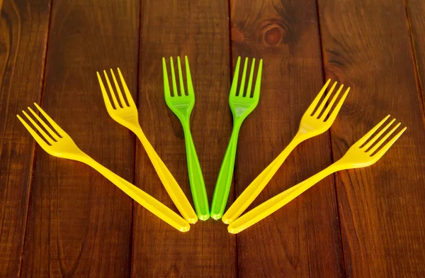 Forchette di plastica colorate monouso su sfondo di legno scuro . — Foto Stock