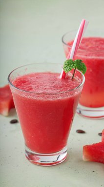 Taze taze karpuz suyu güzel bir bardakta pipetle ve açık arkaplanda nane yaprağıyla.