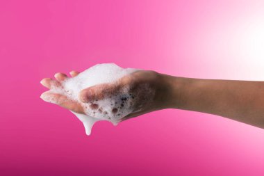 El hijyeni. Covid-19 'un önlenmesi. Pembe arka planda sabunlu köpüklü kadın eli.