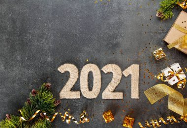 Üst Manzara. 2021 yılının dekoratif yazıtları, sicim ve altın hediyeler, kurdeleler, yılanbalığı ve süslemeler, karanlık bir arka planda noel dalları ve konfetileri.