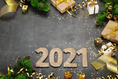 Üst Manzara. Mutlu yıllar 2021. Altın yılanlı ve kurdeleli parlak kart, karanlık arka planda noel hediyeleri.