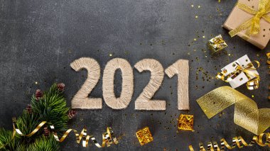 Üst Manzara. Parlak altın yeni yıl kartı hediyeler ve koyu arkaplanda 2021 yazıları, Noel süsleri