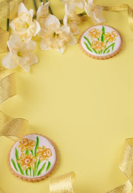 Şenlikli bahar kompozisyonu. El yapımı zencefilli kurabiye, nergis ve altın kurdele.