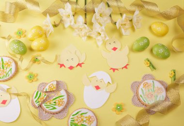 Mutlu Paskalyalar. Elle boyanmış zencefilli ekmek, paskalya yumurtaları, sarı arka planda bahar çiçekleri.