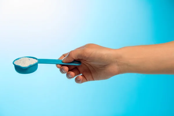 Washing powder in measuring cup in hand — Stock Photo, Image