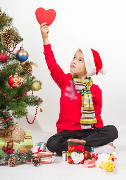 Niño se sienta bajo el árbol de Navidad — Foto de Stock