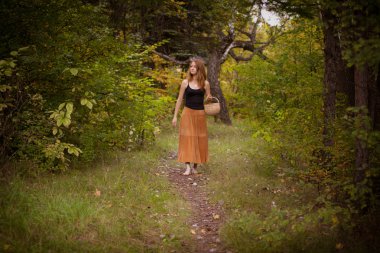 Kızıl saçlı genç kız ormanda yürür bir sepet ile